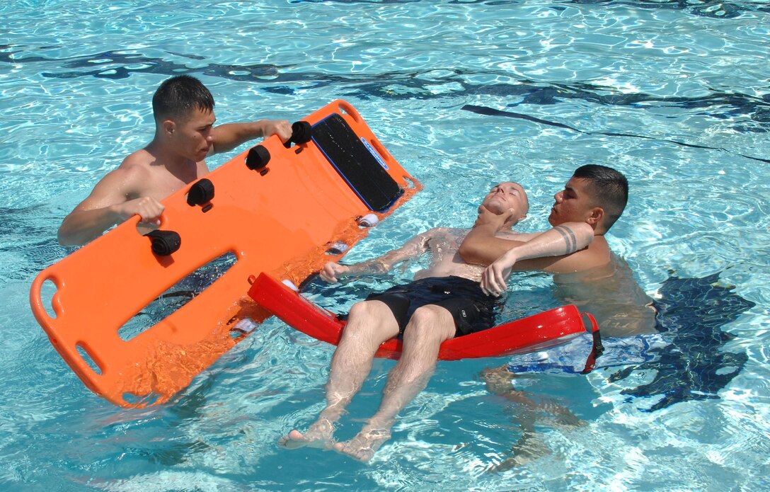 Sgt. Thomas Over, base license noncommissioned officer, Garrison Mobile Equipment, Marine Corps Logistics Base Albany (right), holds the neck of Staff Sgt. Michael Murphy, operations chief, Marine Corps Exchange, Marine Corps Community Services, MCLB Albany, while Cpl. Marcos Noyola, supply administrative clerk, Operations Directorate, Marine Corps Logistics Command, slides a backboard underneath Murphy with a simulated spinal injury during an American Red Cross lifeguard certification course for active-duty Marines, here, June 4-6.