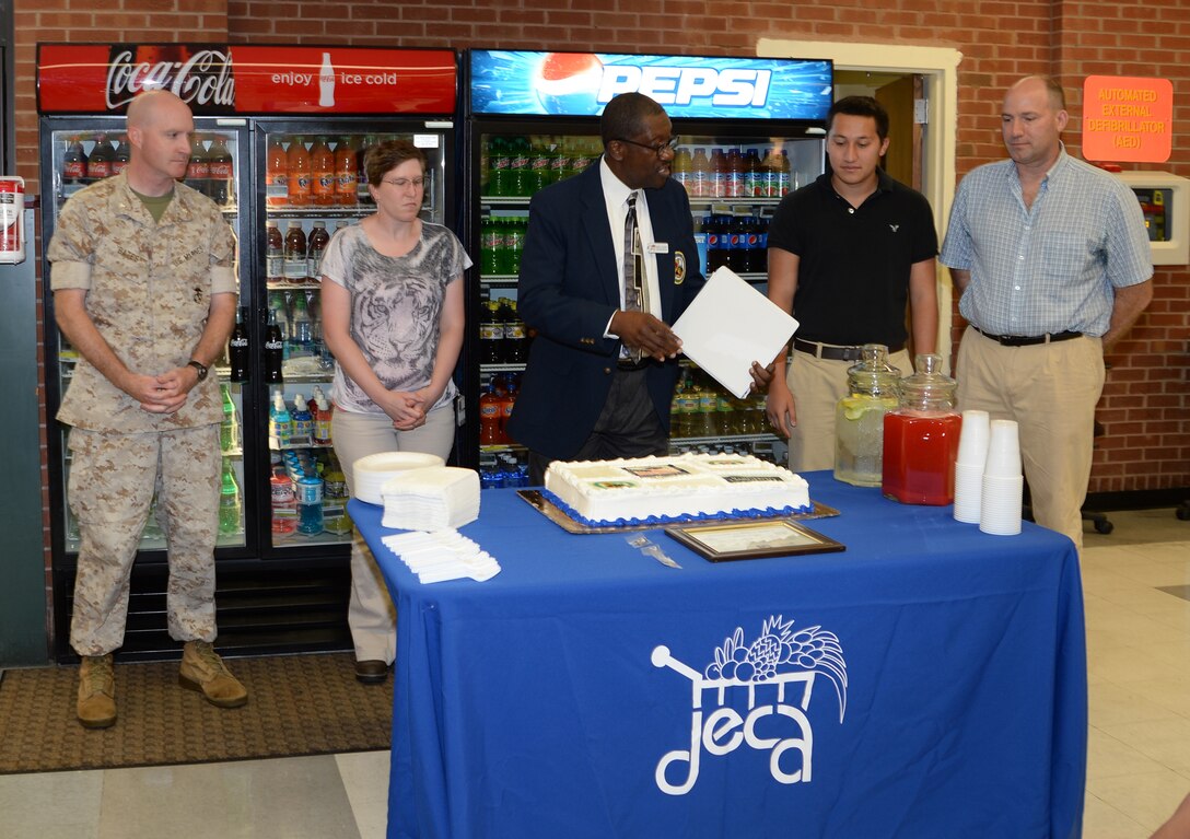 Philip Long (second from right) receives a $2,000 award as Defense Commissary Agency’s 2014 scholarship recipient during a ceremony held in his honor at the Marine Corps Logistics Base Albany Commissary, June 12. Pictured from left are: Lt. Col. Daniel Bates, executive officer, MCLB Albany; Amanda Edwards with Dunham and Smith Agencies; Ernest Beckwith, assistant commissary officer, MCLB Albany, presented the award. Long’s father, Army reservist Chief Warrant Officer 2 Paul Long (far right) was also present for the ceremony.