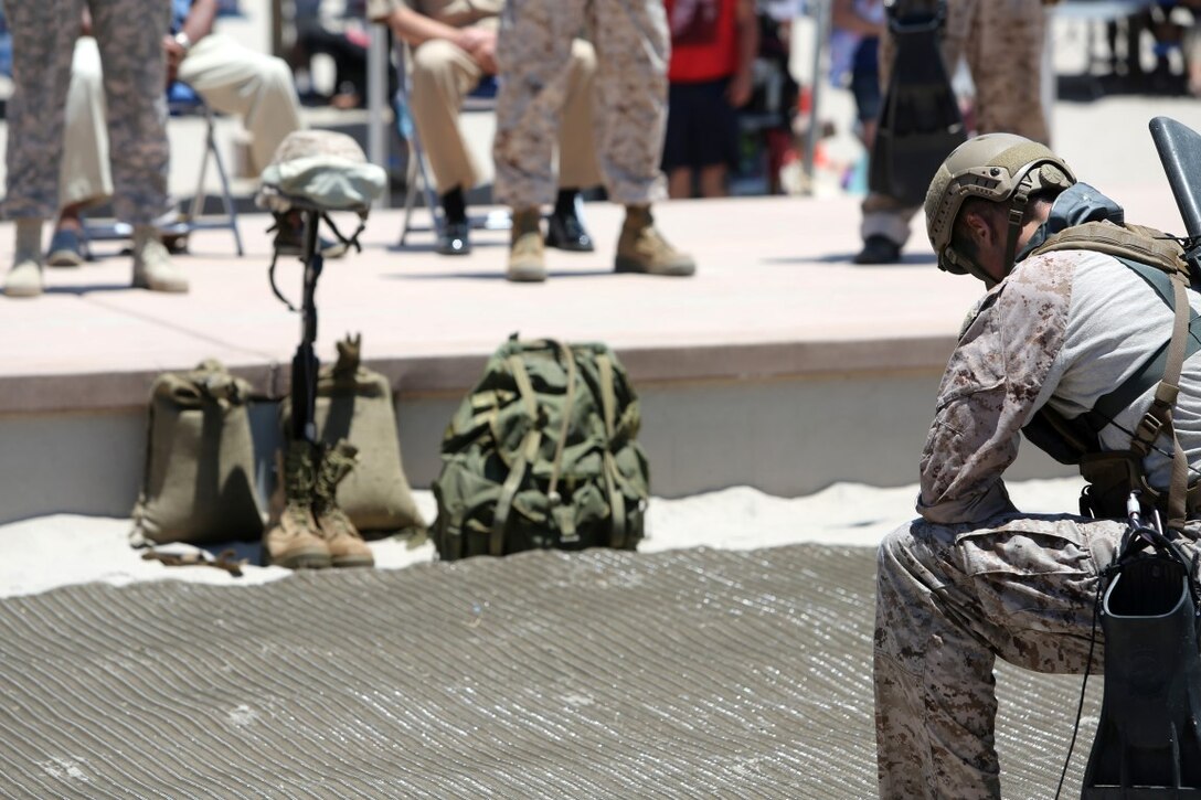 A Special Amphibious Reconnaissance Corpsman, or SARC, kneels in front of a battlefield cross during the 116th Hospital Corps birthday ceremony aboard Camp Pendleton, Calif., June 13, 2014. The battlefield cross was built in memory of fallen sailors and Marines. (U.S. Marine Corps photo by Lance Cpl. David Silvano/released)