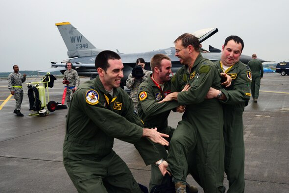 U.S. Air Force Col. Stephen Williams, 35th Fighter Wing commander, is aggressively met by three 35 FW pilots after completing his fini-flight at Misawa Air Base, Japan, June 16, 2014. A pilot’s fini-flight has become a U.S. Air Force tradition, and celebrates milestones with champagne or similar, a toast and dowsing with water from a fire truck for the aircraft and aircrew. Usually, family or families of the departing aircrew or personnel also meet them on the flightline and douse them with water. (U.S. Air Force photo/Senior Airman Derek VanHorn)