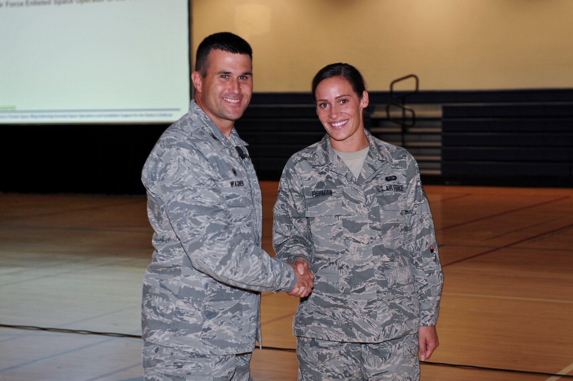 Col. John Wagner, 460th Space Wing commander, left, congratulates Staff Sgt. Diana Fishman, Mile High Honor Guard assistant flight chief, for winning the Chief Master Sergeant of the Air Force Base Honor Guard Member of the Year Award June 18, 2014, at the fitness center on Buckley Air Force Base, Colo. This Air Force level award recognized a base-level honor guard member for their significant contributions in the area of military honors and ceremonies. (U.S. Air Force photo by Senior Airman Phillip Houk/Released)