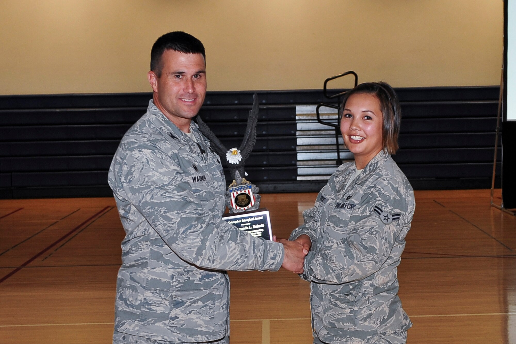 Col. John Wagner, 460th Space Wing commander, left, presents the Kristopher Mansfield Award to,  Airman 1st Class Amanda Belarde, 460th SW military justice paralegal, at the 460th SW commanders call June 18, 2014, at the fitness center on Buckley Air Force Base, Colo. The Mansfield Award is presented each year to an Airman who dedicates themselves to the reduction of alcohol-related incidents in their community. (U.S. Air Force photo by Senior Airman Phillip Houk/Released)