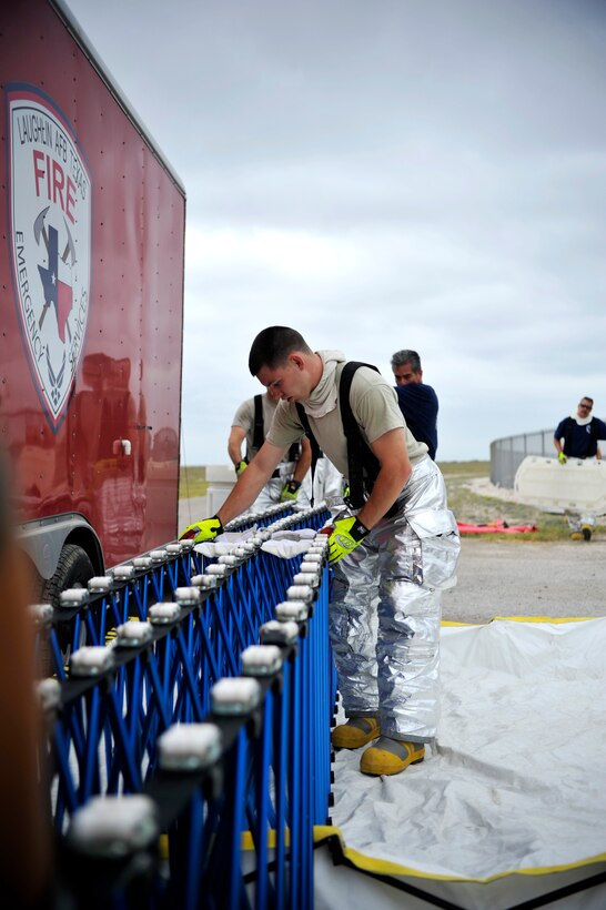 Airman 1st Class Lucas Gouldner, 47th Civil Engineer Squadron firefighter, sets up a section of the decontamination station for a joint unit response training event on Laughlin Air Force Base, Texas, June 17, 2014. Human decontamination is the process of cleansing the human body to remove contamination by hazardous materials including chemicals, radioactive substances and infectious material. (U.S. Air Force photo/Staff Sgt. Steven R. Doty)(Released)