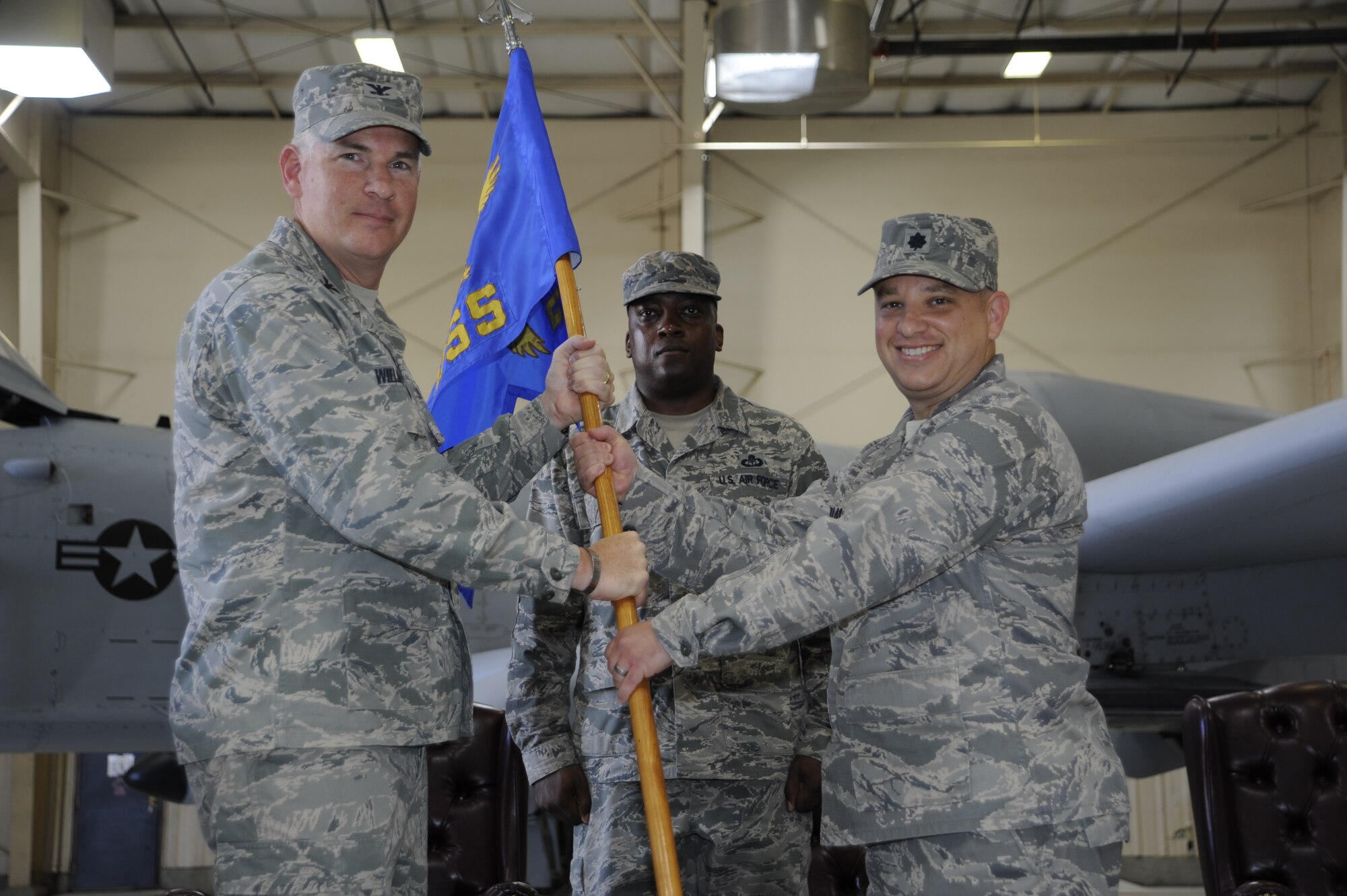 U.S. Air Force Col. Philip Wielhouwer, 355th Operations Group commander, passes the guidon to Lt. Col. Todd Perlman as he assumes command of the 355th Operations Support Squadron at Davis-Monthan Air Force Base, Ariz., June 19, 2014. Passing the guidon is a traditional military custom which symbolizes the relinquishment and assumption of command of a military organization. (U.S. Air Force photo by Airman 1st Class Betty R. Chevalier/Released)
