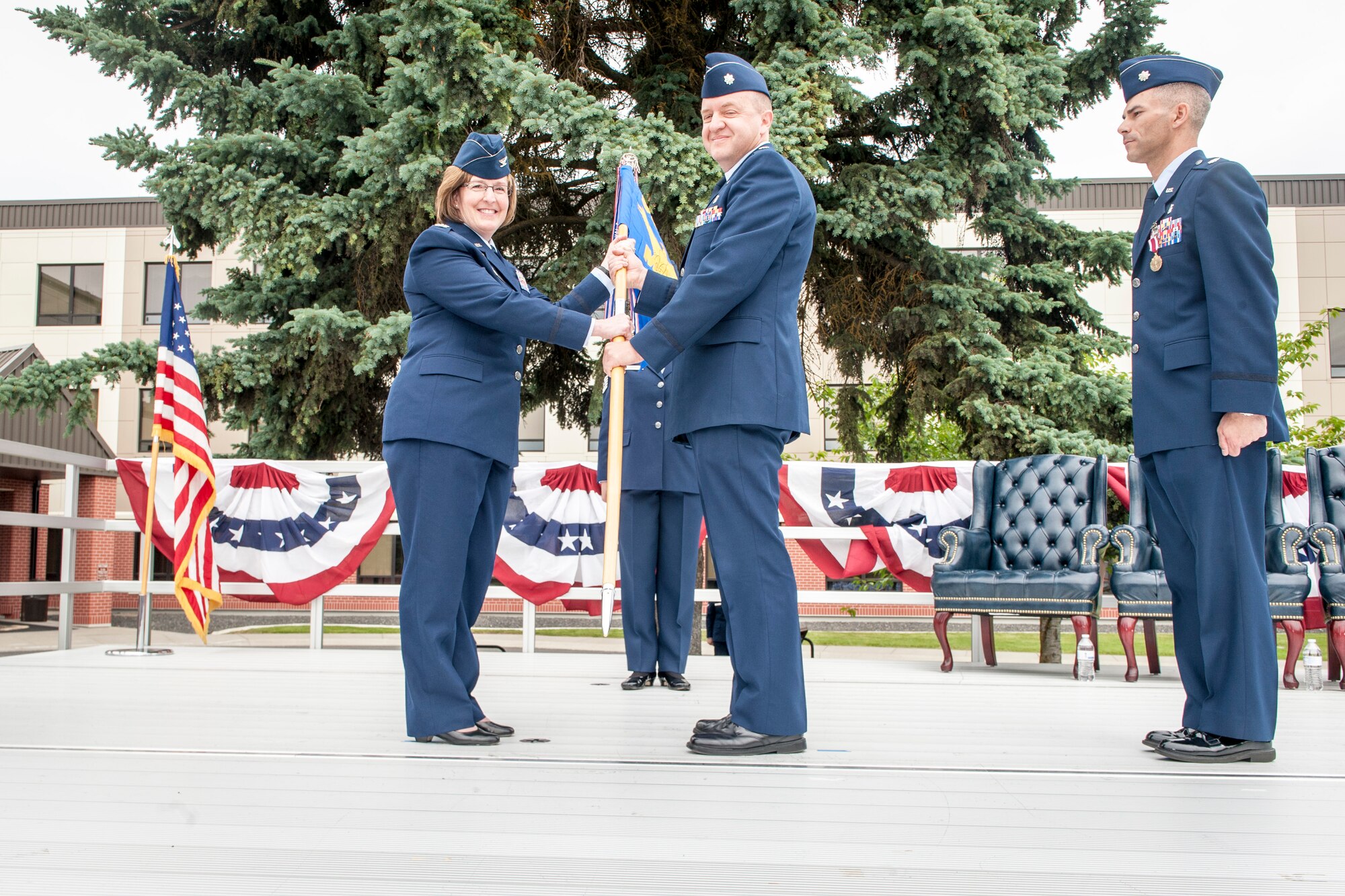 Lt. Col. Dane Campbell takes the guidon from Col. Robin Schultze as Lt. Col. Jason Lennen watches during the 92nd Medical Operations Squadron change of command ceremony at Fairchild Air Force Base, Wash., June 19, 2014. A change of command is a military tradition that represents a formal transfer and responsibility for a unit from one commanding officer to another. Schultze is the 92nd Medical Group commander. Campbell now serves as the 92nd MDOS commander and comes to Fairchild after serving as the 60th Medical Operations Squadron mental health flight commander at Travis Air Force Base, Calif. Lennen and his family leave Fairchild for the U.S. Air Force War College at Maxwell Air Force Base, Ala. (U.S. Air Force photo by Staff Sgt. Benjamin W. Stratton/Released)
