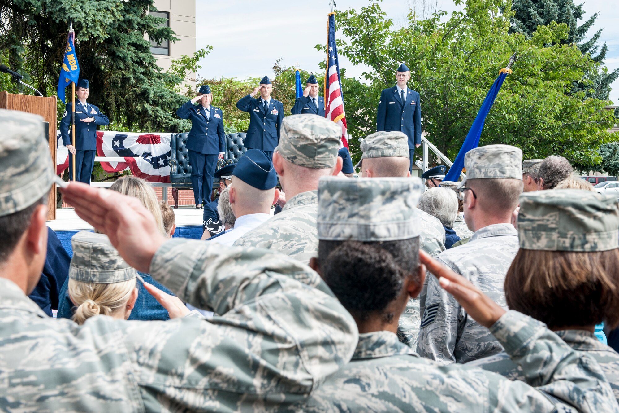 Members of the 92nd Medical Operations Squadron and Team Fairchild salute during the singing of the national anthem before the 92nd MDOS change of command ceremony at Fairchild Air Force Base, Wash., June 19, 2014. A change of command is a military tradition that represents a formal transfer and responsibility for a unit from one commanding officer to another. The passing of the guidon from an outgoing commander to an incoming one ensures that the unit and its Airmen is never without official leadership, a constitution of trust, and also signifies an allegiance of soldiers to their unit’s commander. (U.S. Air Force photo by Staff Sgt. Benjamin W. Stratton/Released)