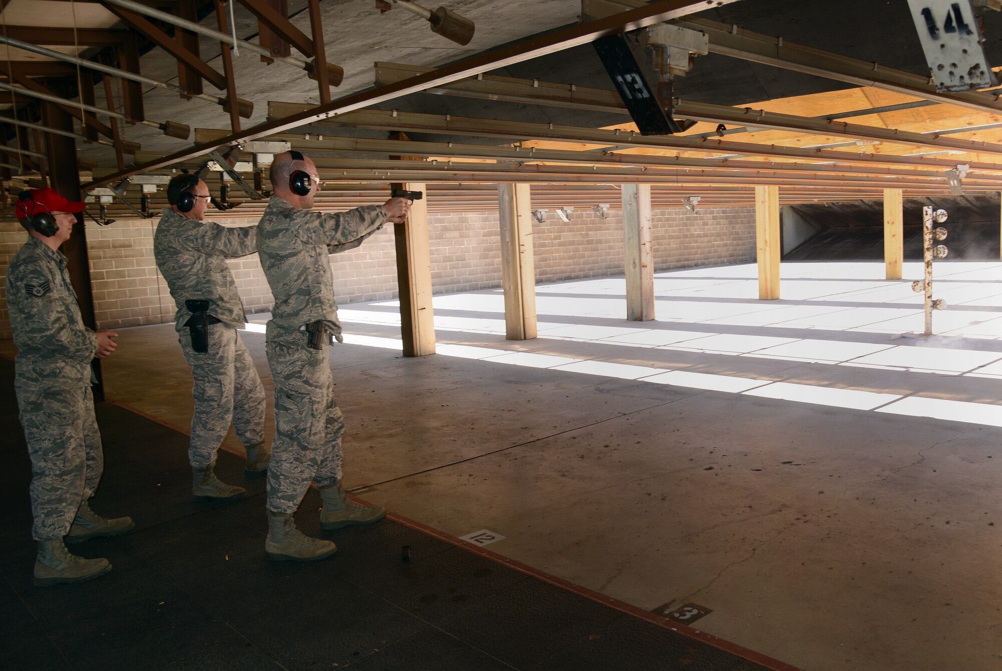 Above: Under the watchful eye of range official Staff Sgt. Matthew Leake, left, Air Force Sustainment Center Commander Lt. Gen. Bruce Litchfield, center, and 72nd Air Base Wing and Tinker Installation Commander Col. Christopher Azzano compete in a friendly shooting competition of their own at the CATM gun range last Friday. (Air Force photo by Kelly White)