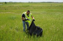 Tech. Sgt. Chris Lucero, 348th Reconnaissance Squadron commander's support staff NCO in charge, bags garbage found on the roadside outside of Grand Forks, N.D., June 18, 2014. As part of the Adopt-a-Highway program, the 348th RS provides volunteers to clean a three-mile stretch of Highway 2. (U.S. Air Force photo/Staff Sgt. David Dobrydney)