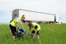 Airmen 1st Class Nina Poli and Robert Barnett, 348th Reconnaissance Squadron schedulers, remove trash from the side of Highway 2 near Grand Forks, N.D., June 18, 2014. Twelve volunteers from the 348th RS collected 26 bags of garbage from three miles of road. (U.S. Air Force photo/Staff Sgt. David Dobrydney)
