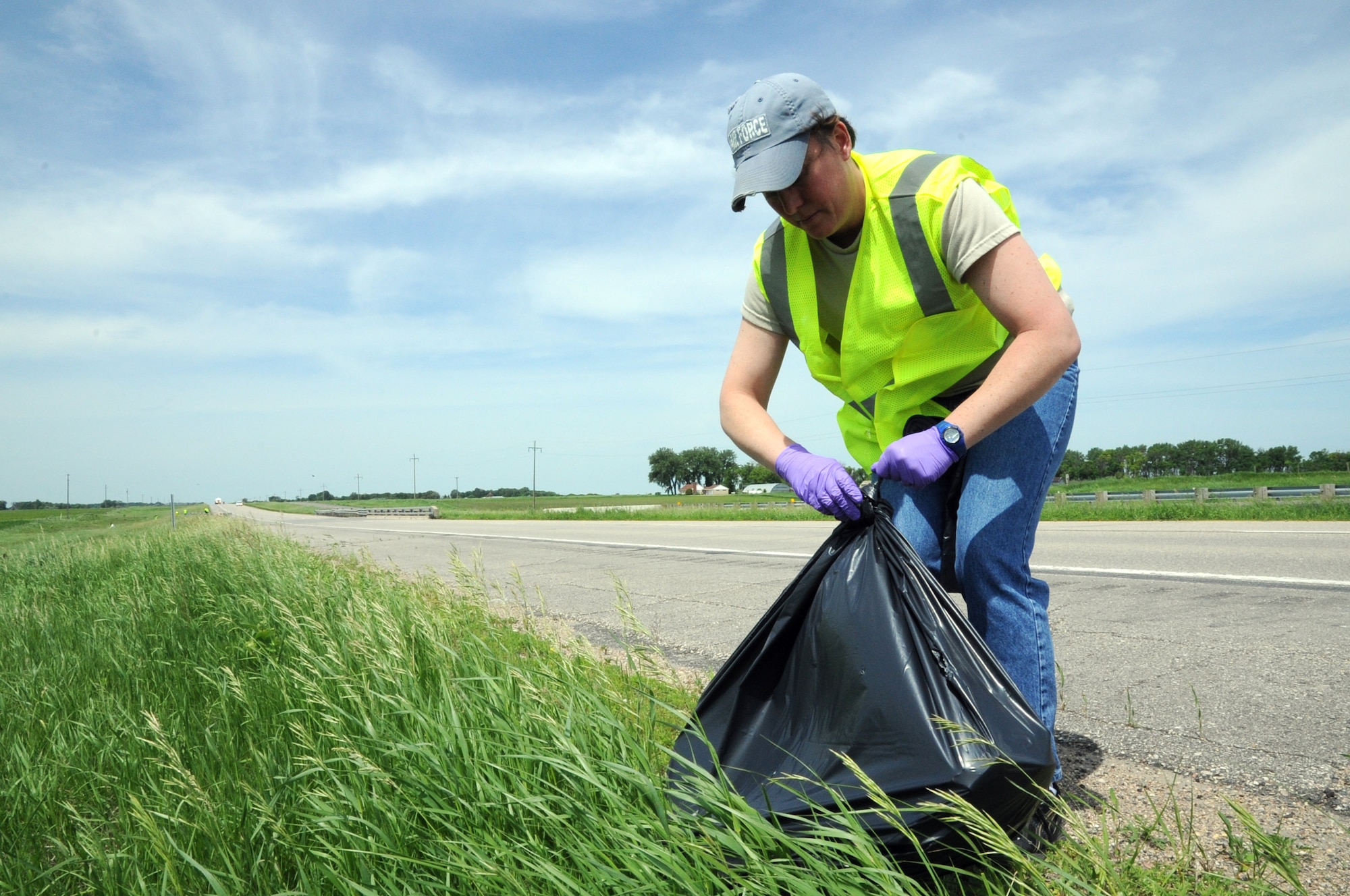Master Sgt. Cathryn Acklin, 348th Reconnaissance Squadron, ties off a bag of trash on the side of Highway 2 outside of Grand Forks, N.D., June 18, 2014. The 348th RS is participating in the Adopt-a-Highway program, removing litter from a three-mile stretch of road. (U.S. Air Force photo/Staff Sgt. David Dobrydney)