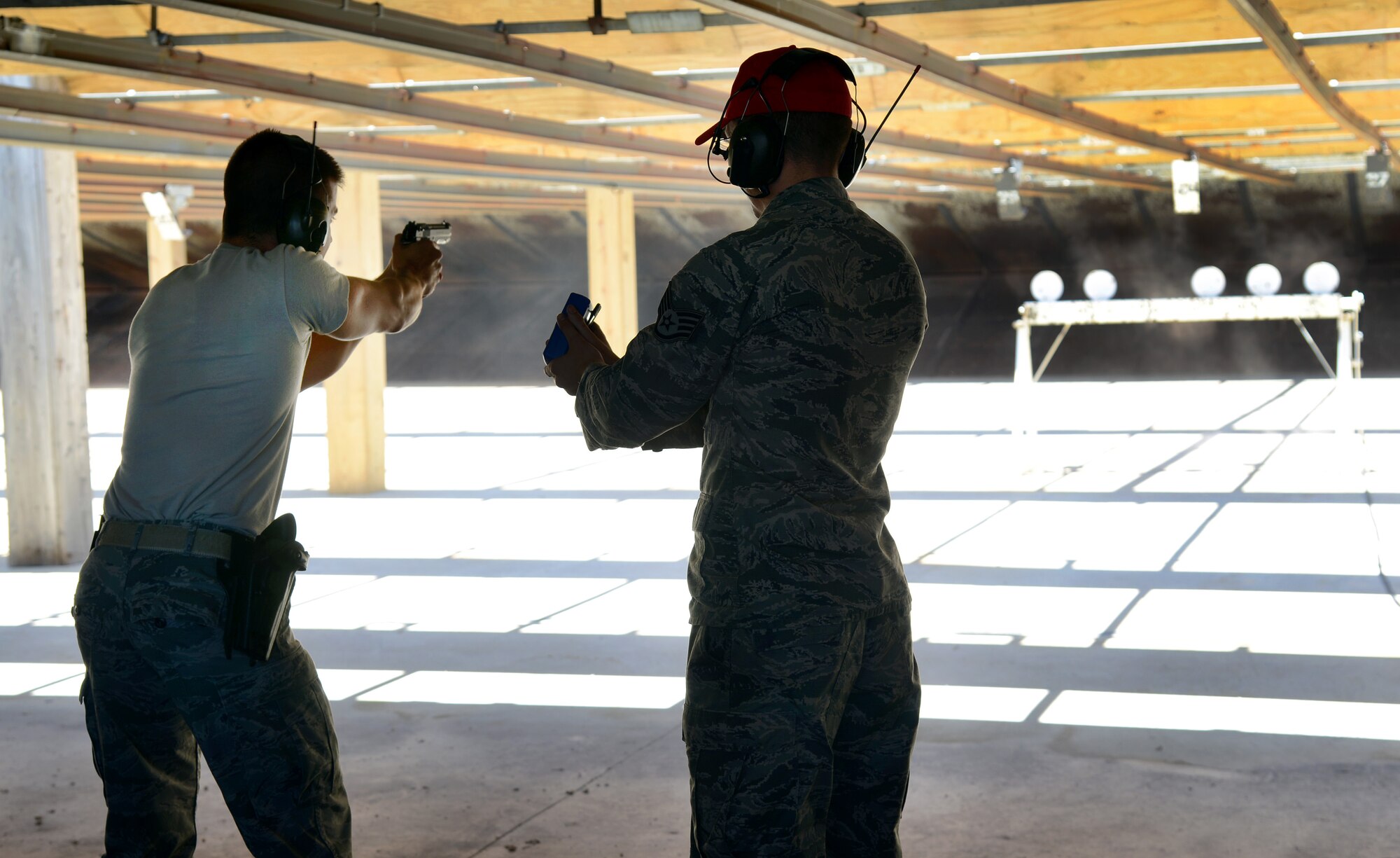 Staff Sgt. Michael Enderud, 72nd Security Forces Squadron, rapidly fires his pistol while range official Staff Sgt. Matthew Leake times him. Participants in the speed-shooting competition at the CATM gun range last Friday each shot two 5-round magazines at 6 targets until they all fell down or the until the shooters were out of ammo. The fastest shooter knocked down all 6 targets in 6 seconds. (Air Force photos by Kelly White)