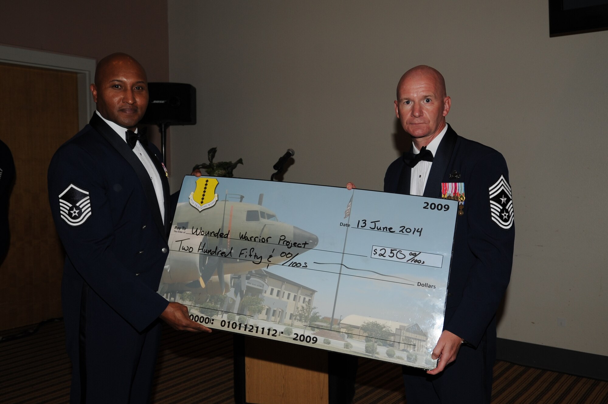 GOODFELLOW AIR FORCE BASE, Texas -- Master Sgt. Marvin L. Hawkins, 17th Medical Operations Squadron superintendent, presents Chief Master Sgt. Thomas F. Good, 17th Training Wing Command Chief, with a $250 check for the Wounded Warrior Project during the Senior NCO Induction Ceremony at the Event Center here June 13. The Goodfellow Air Force Base Top 3 donated the check on behalf of Good who was the guest speaker. (U.S. Air Force photo/ Staff Sgt. Laura R. McFarlane)