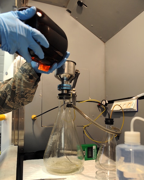 Staff Sgt. Jason Flowers, 2nd Logistics Readiness Squadron fuels laboratory technician, pours a fuel sample into a bottling assembly to test the sample for particles on Barksdale Air Force Base, La., June 18, 2014. The assembly creates a vacuum seal in the flask pulling the fuel through a membrane filter leaving behind particles for analysis. (U.S. Air Force photo/Senior Airman Benjamin Gonsier)