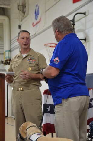 Master Chief Petty Officer Robert Bostic, Naval Consolidated Brig Charleston command master chief, presents a check on behalf of the NCBC Senior Enlisted Association, in the amount of $750, to Rick Hairston, Canines for Service president, June 19, 2014, at the NCBC on Joint Base Charleston, S.C. (U.S. Air Force photo/Eric Sesit) 