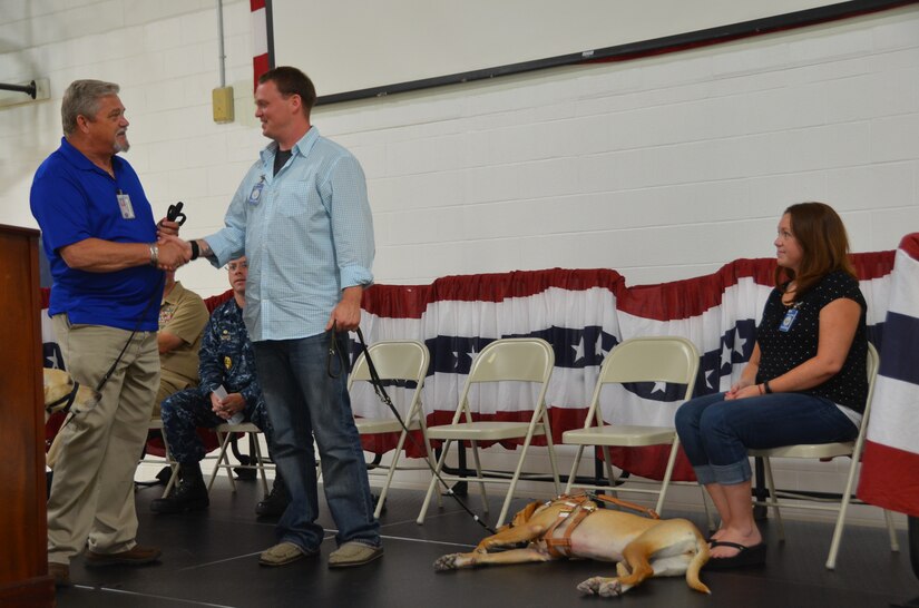 Retired U.S. Marine Corps Sgt. Kyle Miller, from Indianapolis, Ind. (center), and his wife Vanessa, receive congratulations from Rick Hairston, Canines for Service president, as Miller takes ownership of Ava, a 21-month old lab mix, June 19, 2014, at the Naval Consolidated Brig Charleston. Ava was trained at the NCBC in association with Canines for Service Program and will serve as Miller’s canine companion, providing him with greater mobility and assisting his transition back into civilian life while also providing him a greater sense of independence and hope. (U.S. Air Force photo/Eric Sesit) 
