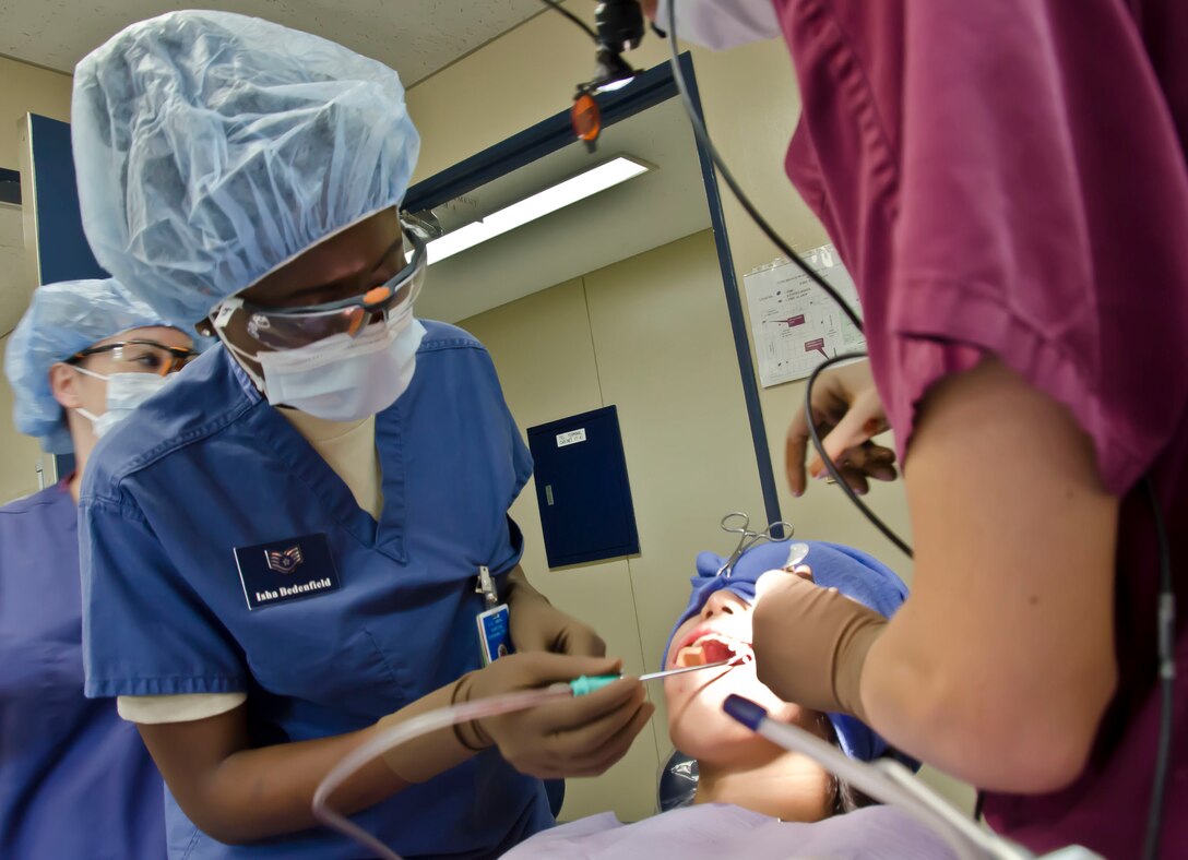 U.S. Air Force Staff Sgt. Isha Bedenfield, a dental technician with the 126th Medical Group, Illinois Air National Guard, assists U.S. Navy Lt. Amanda Rice on an oral surgery procedure at Naval Air Facility Atsugi, Japan, June 11, 2014. The surgery involved the extraction of four wisdom teeth to prevent infection. (Air National Guard photo by Senior Airman Laura Muehl)