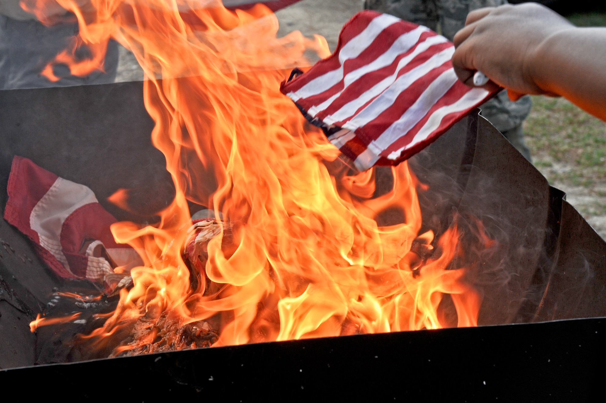 A Team Seymour member retires a flag by placing it on the flame June 14, 2014, at Seymour Johnson Air Force Base, North Carolina. U.S. code dictates that once a U.S. flag is no longer in good standing condition it will be replaced with a new one and the old will be respectfully laid to rest. (U.S. Air Force photo/Airman 1st Class Aaron J. Jenne)