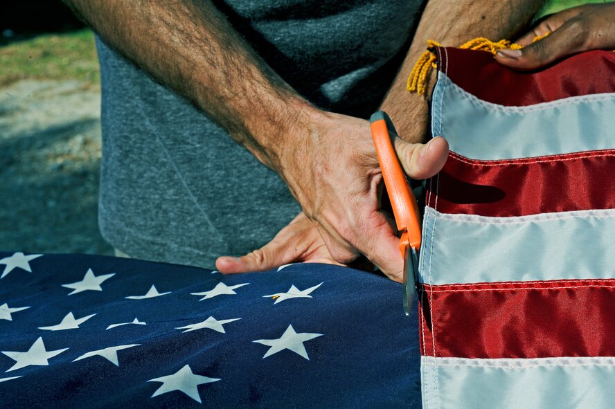 A member of Team Seymour removes the star-spangled blue field from a ceremonial flag during a flag retirement ceremony June 14, 2014, at Seymour Johnson Air Force Base, North Carolina. Following a flags life cycle, when it has been worn, torn or soiled through wear and tear, it is ceremoniously retired, dismantled and incinerated. (U.S. Air Force photo/Airman 1st Class Aaron J. Jenne)