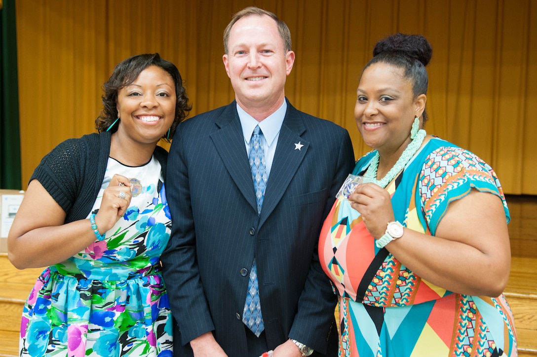 Tia Kenan (left) and Melanie Wheeler (right), Francis T. Evans fifth-grade teachers, receive a coin from John Rogers (center), Joint Base Andrews 844th Communications Group deputy director, at the fifth-grade graduation ceremony, Clinton, Md., June 12. The 844th CG adopted and has sponsored the school for the past three years. The students completed an eight-month mentorship program with Joint Base Andrews Airmen coordinated through the Area Coalitions Education-Excellence program that connects public schools with government, military, private sector and local community volunteers. (U.S. Air Force photo/Aimee Fujikawa)



