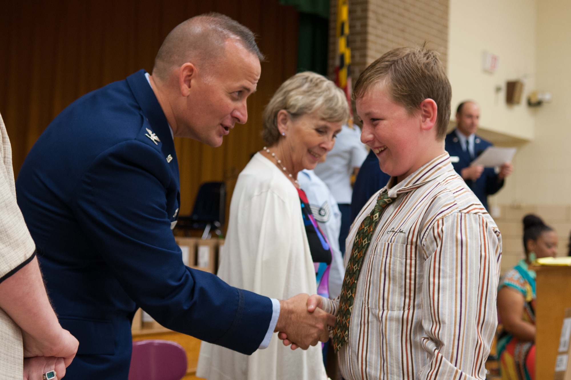 Col. William Knight, 11th Wing/Joint Base Andrews commander, congratulates student Lucas Renfro, at the Francis T. Evans Elementary School fifth-grade graduation ceremony, Clinton, Md., June 12. The students also completed an eight-month mentorship program with Joint Base Andrews Airmen through the Area Coalitions Education-Excellence program that connects public schools with government, military, private sector and local community volunteers. (U.S. Air Force photo/Aimee Fujikawa)
