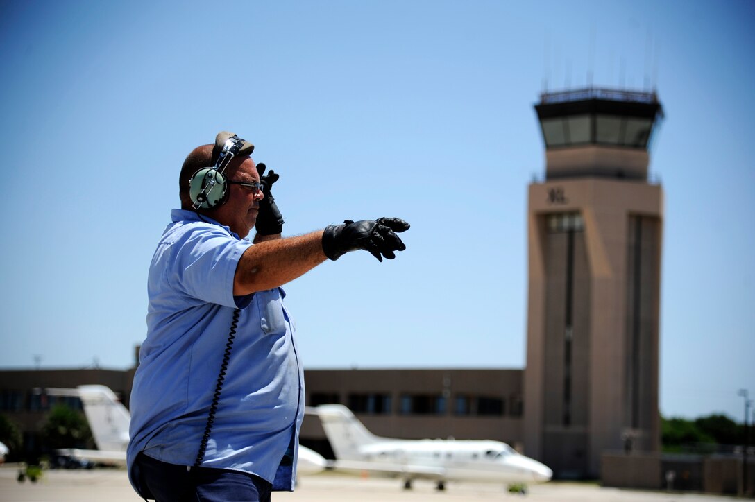 Herman Hidalgo, 47th Maintenance Directorate aircraft servicer, marshals a T-1A Jayhawk at the flight line on Laughlin Air Force Base, Texas, June 10, 2014. The T-1A Jayhawk is a medium-range, twin-engine jet trainer used in the advanced phase of specialized undergraduate pilot training for students selected to fly airlift or tanker aircraft. (U.S. Air Force photo/Staff Sgt. Steven R. Doty)(Released)