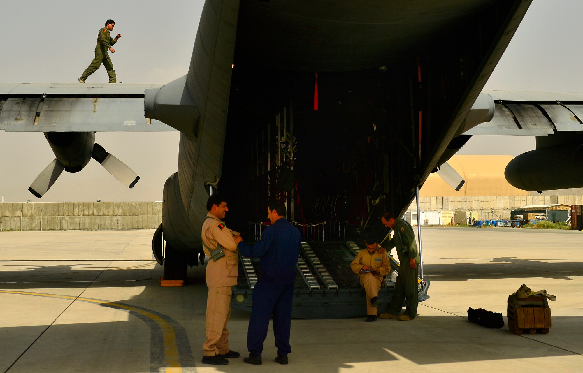 Afghan Air Force 1st Lt. Khial Shinwari, C-130 Hercules aircraft commander, performs a pre-flight inspection on the wing of a C-130 as loadmasters discuss load plans prior to the first-ever all Afghan C-130 flight, Kabul, Afghanistan, June 16, 2014. The aircrew, made up of six Afghan Air Force pilots and loadmasters, successfully completed a mission from Kabul to Kandahar and back. The aircrew successfully planned, executed and accounted for movement of about 120 Afghan personnel, two casualty evacuation patients, luggage and cargo in both directions. The ability for the AAF aircrew to move Afghan National Army Security Forces personnel, cargo, CASEVAC patients and human remains missions is a major accomplishment for both the AAF and NATO Air Training Command – Afghanistan advisors assigned to the 438th Air Expeditionary Wing. This milestone was accomplished eight months earlier than projected. (U.S. Air Force photo by Staff Sgt. Vernon Young Jr.)