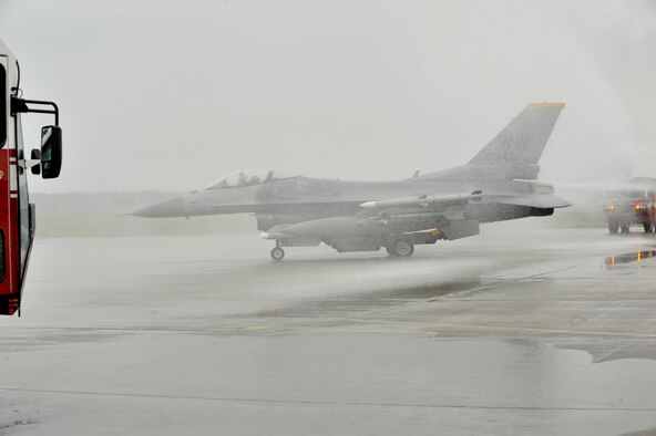U.S. Air Force Col. Matthew Dana taxis his F-16 Fighting Falcon under an arch of water streaming from 35th Civil Engineer Squadron fire trucks during his fini-flight at Misawa Air Base, Japan, June 16, 2014. Hosing of the aircraft during taxi is a tradition said to have originated during World War II and used to commemorate an aviation milestone.  (U.S. Air Force photo/ Staff Sgt. Tong Duong)