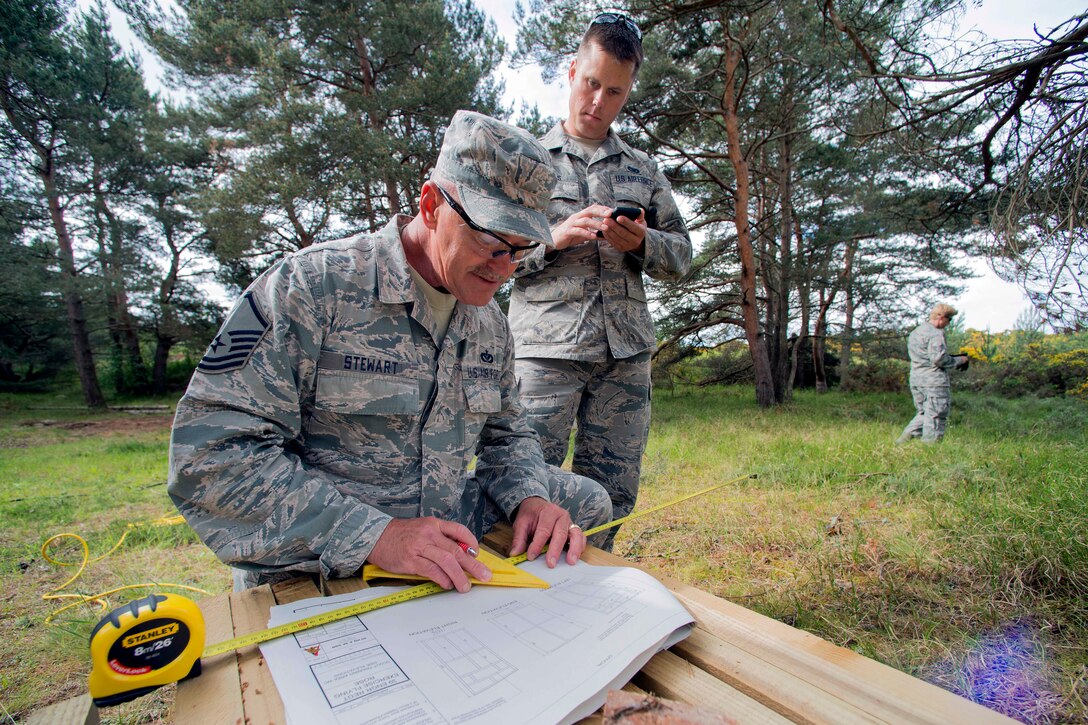 U.S. Air Force Master Sgt. Kelly Stewart, foreground, and U.S. Air Force Airman 1st Class Ryan Harris convert measurements on a set of plans that will be used to construct several water closets during Exercise Flying Rose at Kinloss Barracks in Forres, Moray, Scotland, June 11, 2014. Stewart and Harris are assigned to the Colorado Air National Guard's 140th Civil Engineering Squadron.