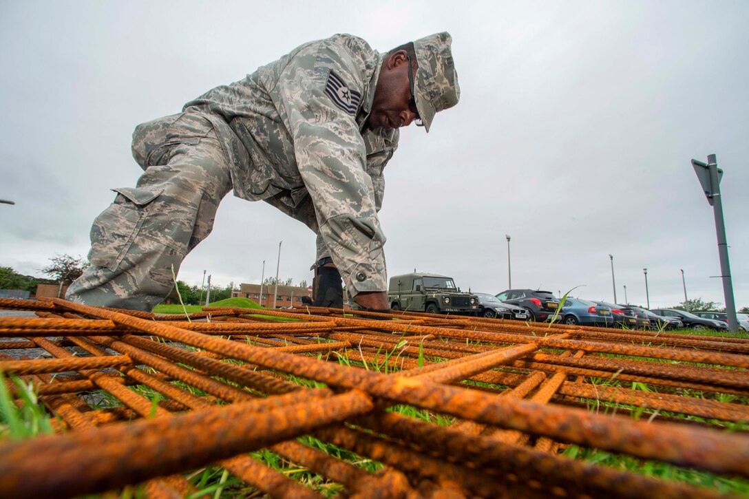 U.S. Air Force Staff Sgt. Terry Kelly unties a stack of rebar that will be used for a new concrete pad that is designed to support large dumpsters during Exercise Flying Rose at Kinloss Barracks in Forres, Moray, Scotland, June 13, 2014. Kelly is assigned to the Georgia Air National Guard's 165th Civil Engineering Squadron.