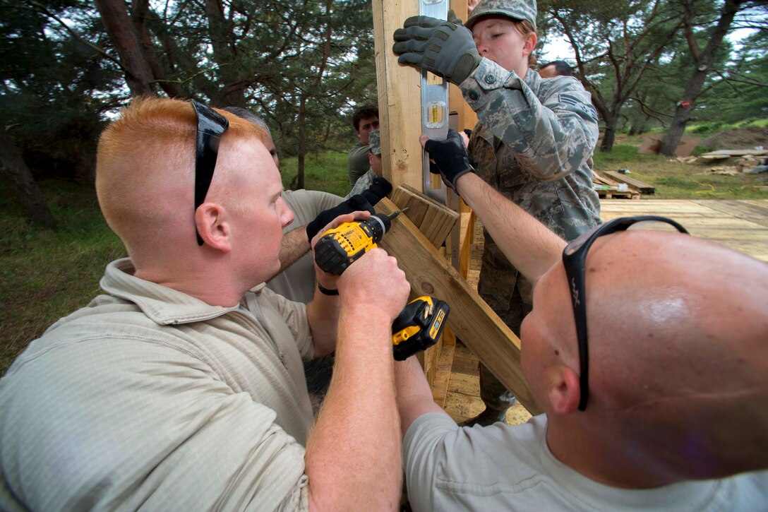 U.S. Air Force Airman 1st Class Justin Bryan, left, U.S. Air Force Senior Airman Ellie Gustafson, center, and U.S. Air Force Tech. Sgt. Neil Elson, right, set a support for the back wall on single room structure that was dissembled so it could be moved to a more suitable site during Exercise Flying Rose at Kinloss Barracks in Forres, Moray, Scotland, June 13, 2014. Bryan, Gustafson and Elson are assigned to the Colorado Air National Guard's 140th Civil Engineering Squadron.