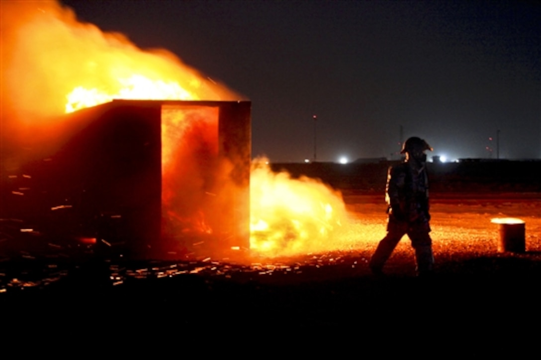 A U.S. Air Force airman sets fire to an empty shipping container to simulate a crashed aircraft during a live-fire exercise at night on Camp Shorabak, Afghanistan, June 7, 2014. 