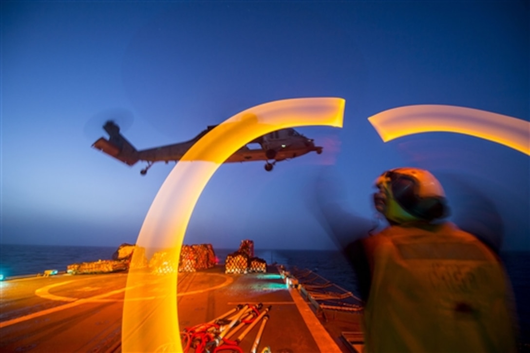 U.S. Navy seaman Clayton Jackson guides an MH-60S Sea Hawk helicopter assigned to Sea Combat Squadron 28 during a night vertical replenishment aboard the guided-missile cruiser USS Philippine Sea in the Arabian Sea, June 11, 2014. Jackson is a boatswain's mate. The Philippine Sea is deployed as part of the George H.W. Bush Carrier Strike Group supporting maritime security operations and theater security cooperation efforts in the U.S. 5th Fleet area of responsibility. 