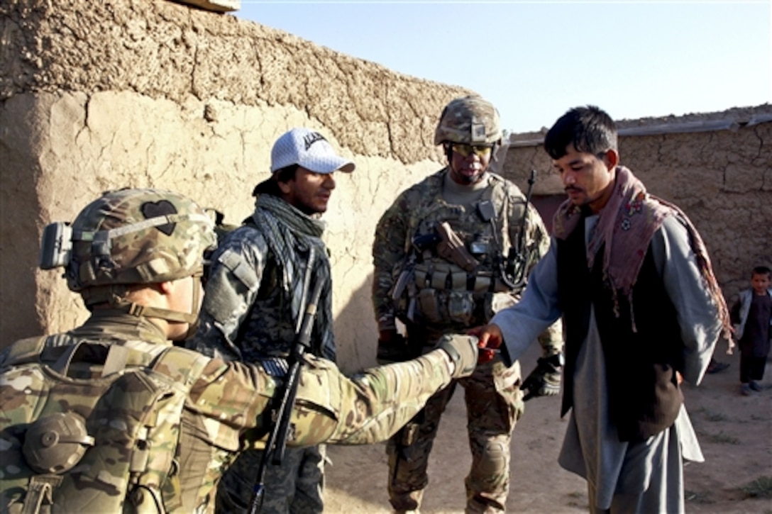 U.S. Army 1st Lt. Matthew White, bottom left, gives an Afghan resident a leaflet as U.S. Army Capt. Rodney Freeman looks on while patrolling through Petawa village in Afghanistan's Parwan province, June 13, 2014. White and Freeman are assigned to the 101st Airborne Division's Company A, 1st Battalion, 2nd Brigade Combat Team, Task Force Strike. The soldiers patrolled to disrupt enemy activity during the Afghan elections. 