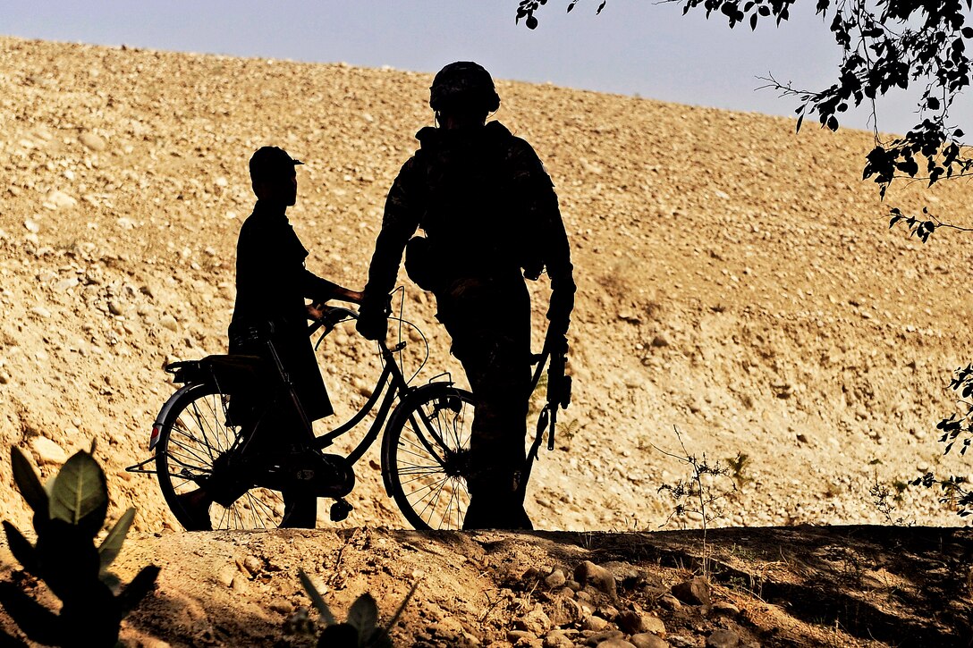 U.S. Army Sgt. Sterling Shearer walks with an Afghan boy in the Alisheng district in Afghanistan's Laghman province, Sept. 12, 2011. Shearer is assigned to the Laghman Provincial Reconstruction Team.  
