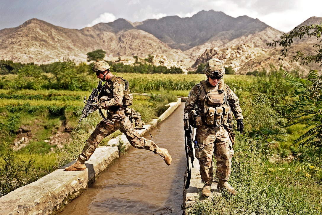 U.S. Army Spc. Jake Amato jumps over a canal while he and Sgt. Sean Matthews look for triggermen in the Alisheng district in Afghanistan's Laghman province, Sept. 12, 2011. Amato and Matthews are assigned to the Laghman Provincial Reconstruction Team.  
