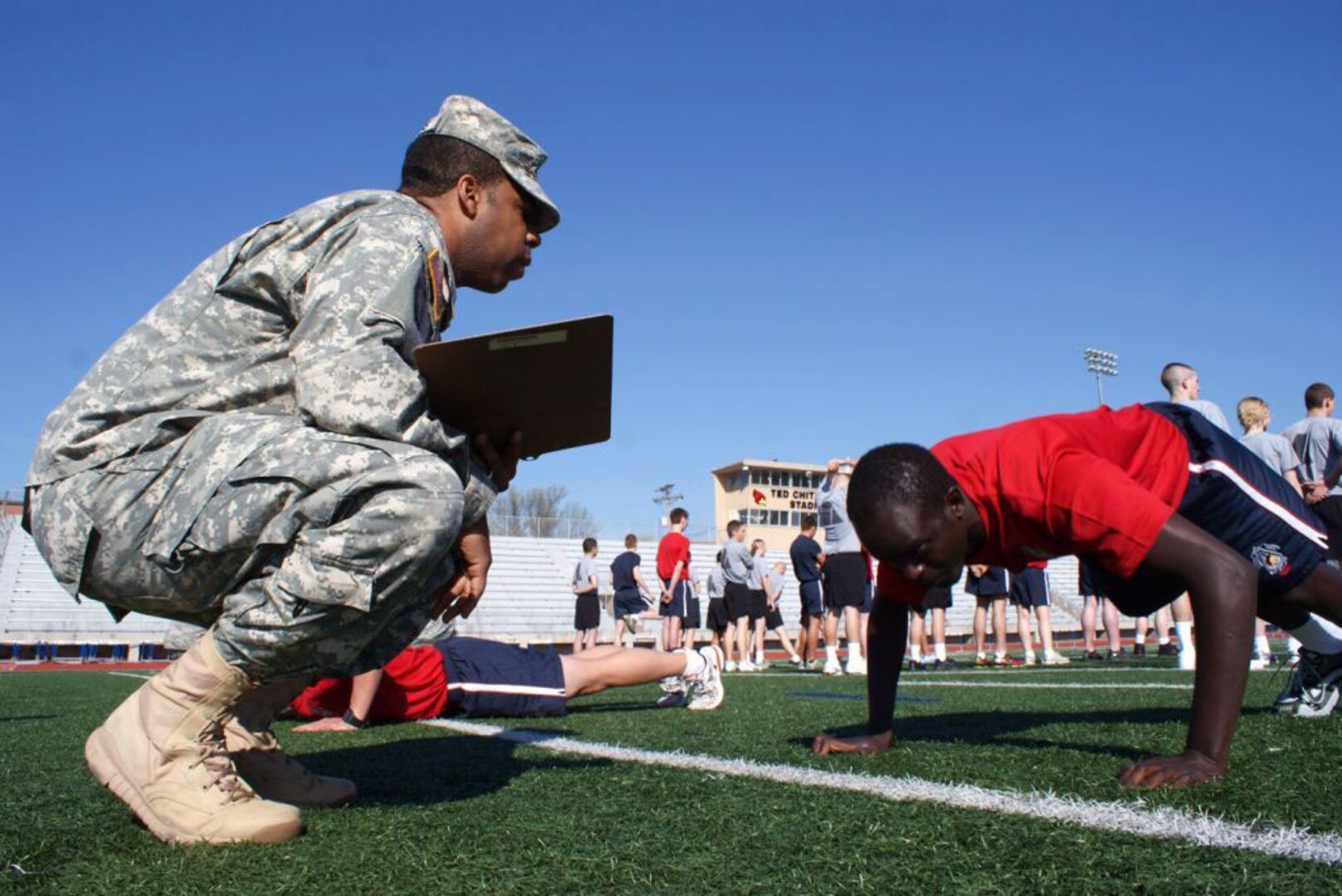 Army Pvt. Paul Baiywo (right) takes his first physical fitness assessment at the Raytown High School track while his recruiter, Army Sgt. Jerry Simons, encourages him to do as many push-ups as he can April 16, 2012.