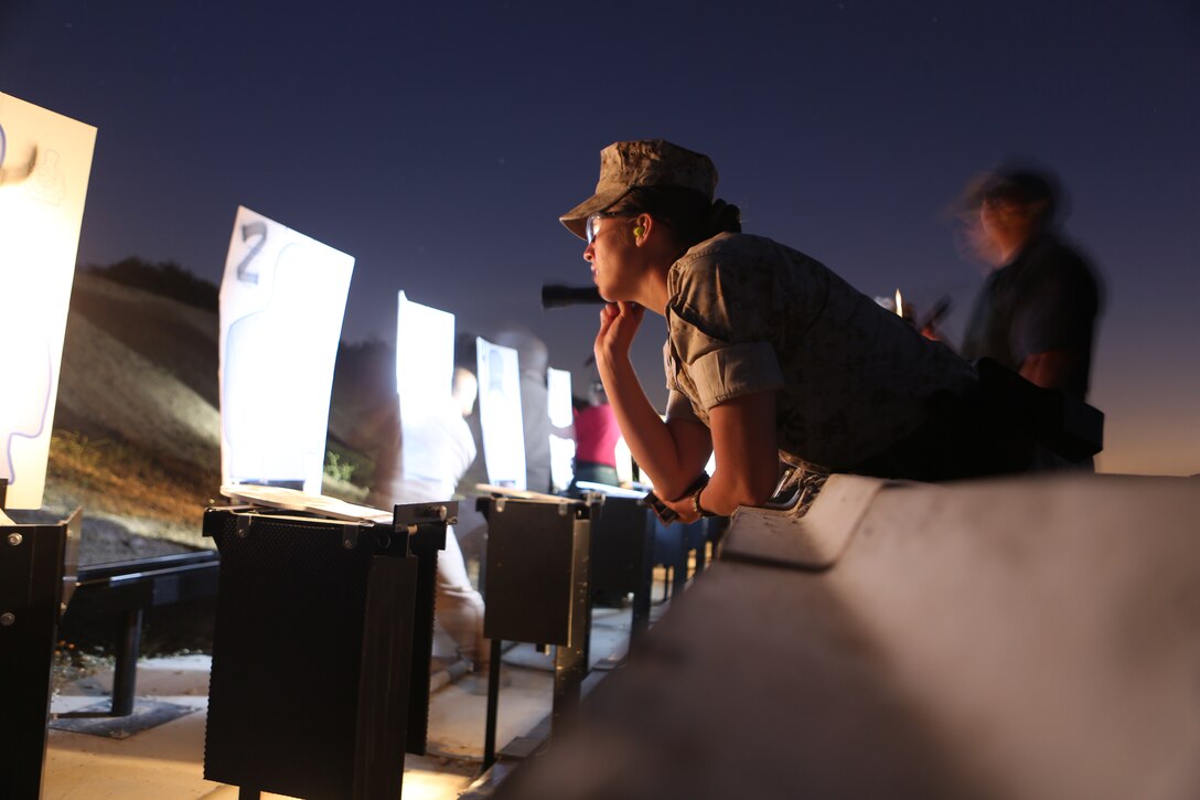 Cpl. Amanda Firth, a military police officer with the Marine Corps Air Station Miramar Provost Marshal’s Office, examines her shots on a target during a  low-light range aboard MCAS Miramar, Calif., June 18. Military police also conducted a practical weapons course as part of the annual training.  