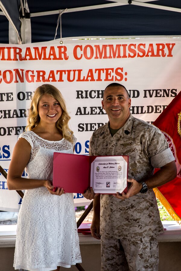 Sgt. Maj. Richard Charron, Marine Corps Air Station Miramar sergeant major, presents a scholarship certificate to Alexis B Childers, scholarship winner, aboard MCAS Miramar, Calif., June 19. The Defense Commissary Agency and the Fisher House Foundation Scholarship award ceremony presented scholarships to the six scholarship winners. 