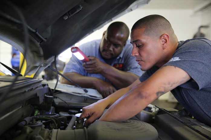 Staff Sgt. Ramiro A. Castanda, drill instructor, Kilo Company, 3rd Recruit Training Battalion, works on his engine with Tracey C. Cluke, mechanic, Auto Hobby Shop aboard Marine Corps Recruit Depot San Diego, June. 18. The Hobby Shop offers everything from car and motorcycle lifts to every tool required for most automotive needs.