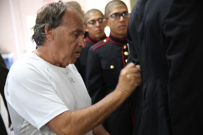 Jack Morgenstern, tailor, marks a recruit's dress blue coat during Bravo Company's initial uniform issue, June 11. Recruits will return when the tailoring process is completed to ensure a correct fit.