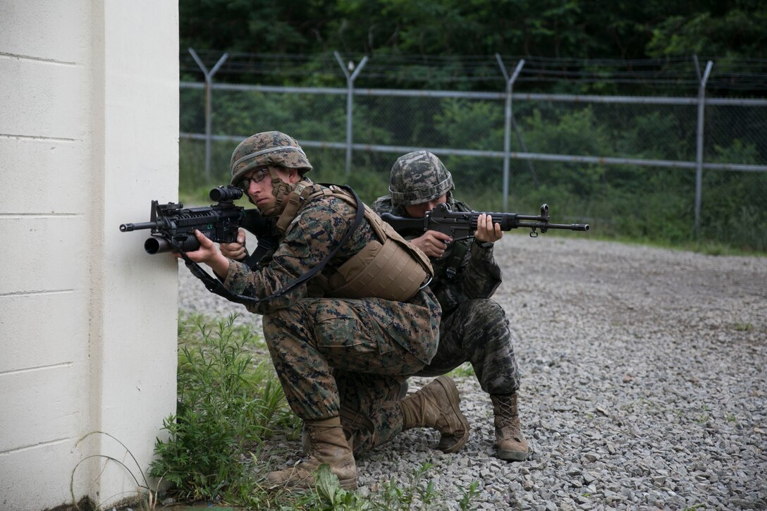 U.S. Marine Lance Cpl. Dallas J. Pontremoli, left, and a Republic of Korea Marine post security June 11 during military operations on urbanized terrain training at the MOUT training center in Pohang, Republic of Korea. The two-day training evolution covered the basics of patrolling through an urban environment, reacting to enemy contact, crossing danger areas, as well as  clearing out rooms, stairwells and buildings. The U.S. Marines are in Pohang to take part in the Korean Marine Exchange Program 14-8, a combined, small-unit training exercise, which enhances the combat readiness and interoperability of ROK-U.S. Marine Corps forces. Pontremoli is a military policeman with Company C, 3rd Law Enforcement Battalion, III Marine Expeditionary Force Headquarters Group, III MEF. The ROK Marine is a military policeman with Military Police Company, 2nd ROK Marine Division. (U.S. Marine Corps photo by Lance Cpl. Drew Tech/Released)