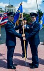 Col. Michael Merritt, 15th Operations Group commander, left, passes the guidon to Lt. Col. Benjamin Menges, 65th Airlift Squadron commander, right, during a change of command ceremony on the Joint Base Pearl Harbor-Hickam flightline June 20, 2014. Menges takes over for Lt. Col. Brian Mackey. (U.S. Air Force photo/Tech. Sgt. Terri Paden)