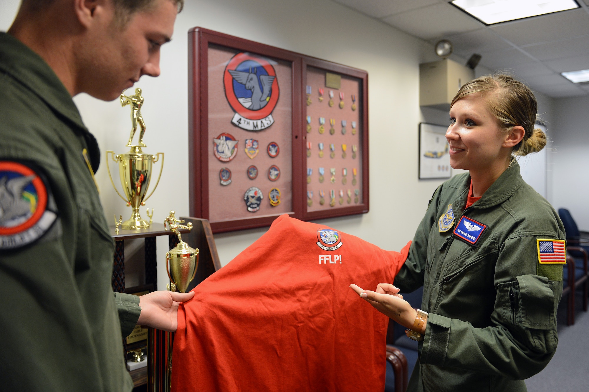 Senior Airman Brooke Breeden, 4th Airlift Squadron loadmaster, shows Airman 1st Class Sam Ware, 4th AS loadmaster, their squadron’s abbreviated motto, “Fly, fight, and live proud” on a morale Friday T-shirt June 20, 2014, at Joint Base Lewis-McChord, Wash. Airmen are allowed to work with their leadership to design a morale T-shirt or flight patch that represents their squadron and its values. (U. S. Air Force photo/Airman 1st Class Jacob Jimenez) 