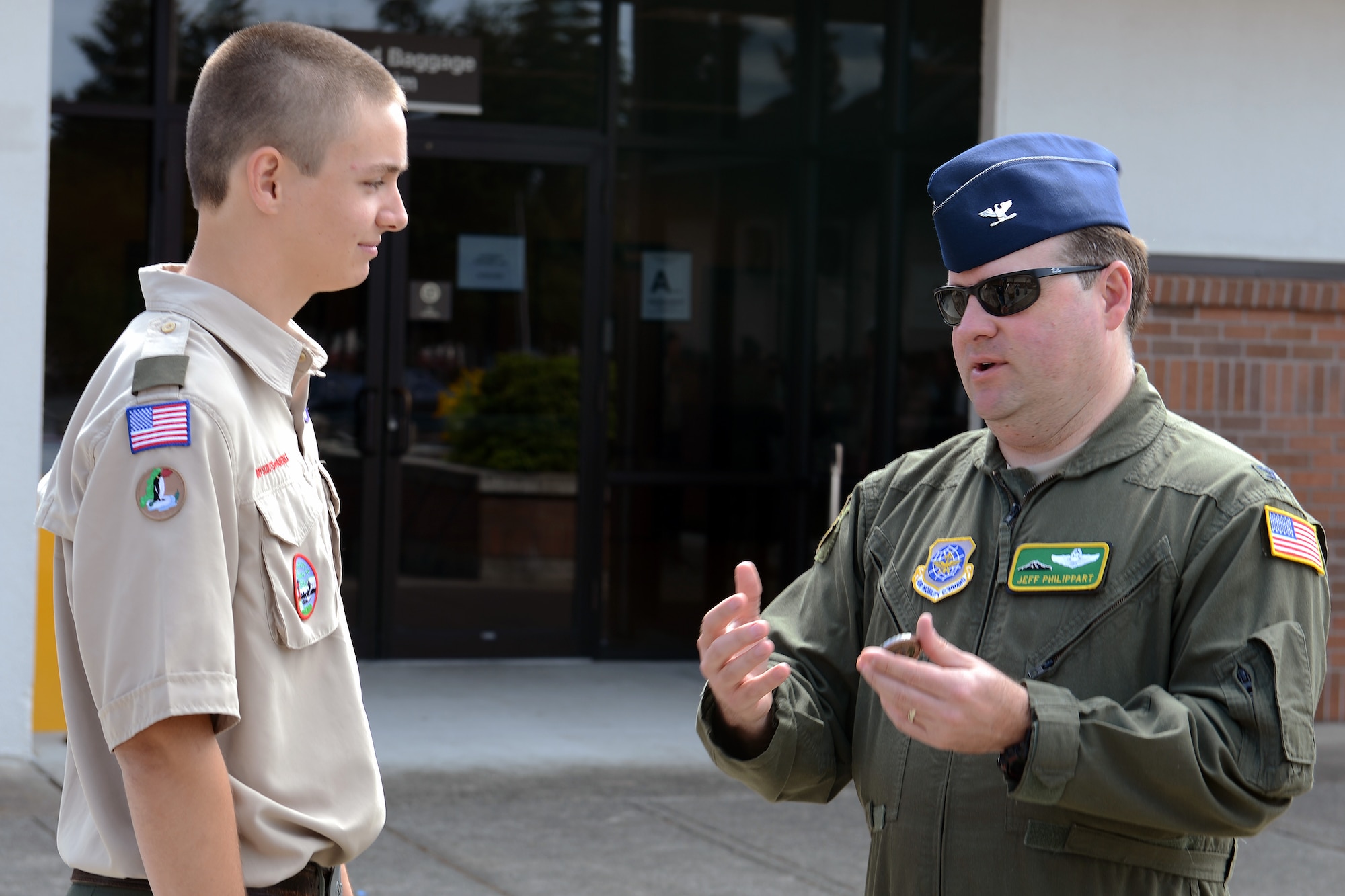 Skyler Liechty (left), from Boy Scout Troop 647, is coined by Col. Jeff Philippart, 62nd Airlift Wing vice commander, after donating two picnic tables from his troop to the USO Shali Center June 20, 2014, at Joint Base Lewis-McChord, Wash. Liechty coordinated and oversaw the project, raised the money and built the tables for the USO. (U.S. Air Force/photo Airman 1st Class Jacob Jimenez) 