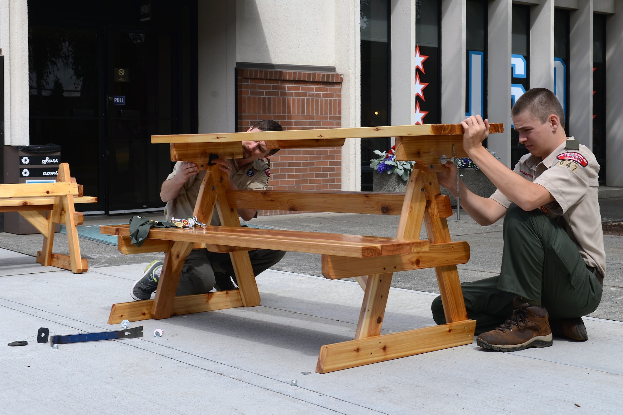 Skyler Liechty (right), and his father, John Liechty from Boy Scout Troop 647, assemble a picnic table in front of McChord Field’s USO Shali Center June 20, 2014, at Joint Base Lewis-McChord, Wash. Skyler Liechty worked more than two weeks with his troop building the two tables for the USO. (U.S. Air Force photo/Airman 1st Class Jacob Jimenez)      