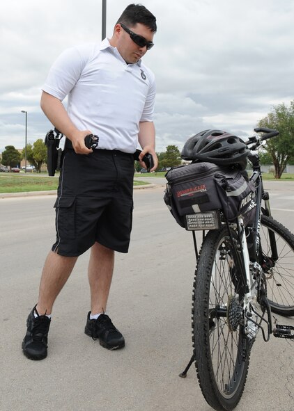 U.S. Air Force Senior Airman Enrique Martinez, 7th Security Forces Squadron team lead, puts on his utility belt before mounting his bike June 9, 2014, at Dyess Air Force Base, Texas. Patrolmen are trained to respond to accidents, security incidents, traffic or law-enforcement situations, natural disasters and medical emergencies. (U.S. Air Force photo by Senior Airman Shannon Hall/Released)