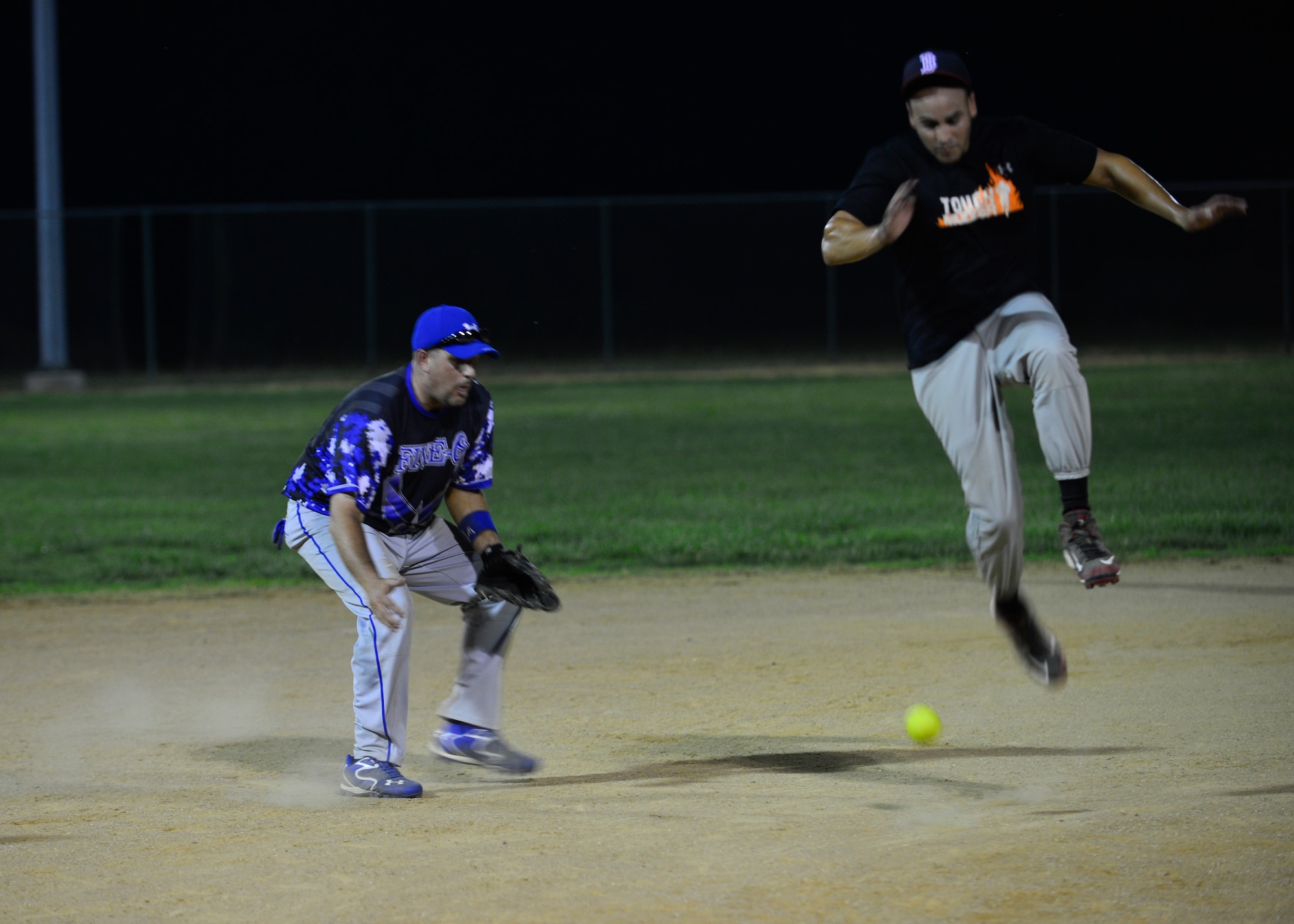 Argenis Diaz, 436th Aerial Port Squadron first baseman, jumps over a softball hit to Rick Barker, 436th Security Forces Squadron shortstop, during an intramural softball game June 18, 2014, at the softball field on Dover Air Force Base, Del. Barker was unable to tag Diaz on the play but made the easy out at second base. (U.S. Air Force photo/Airman 1st Class William Johnson)