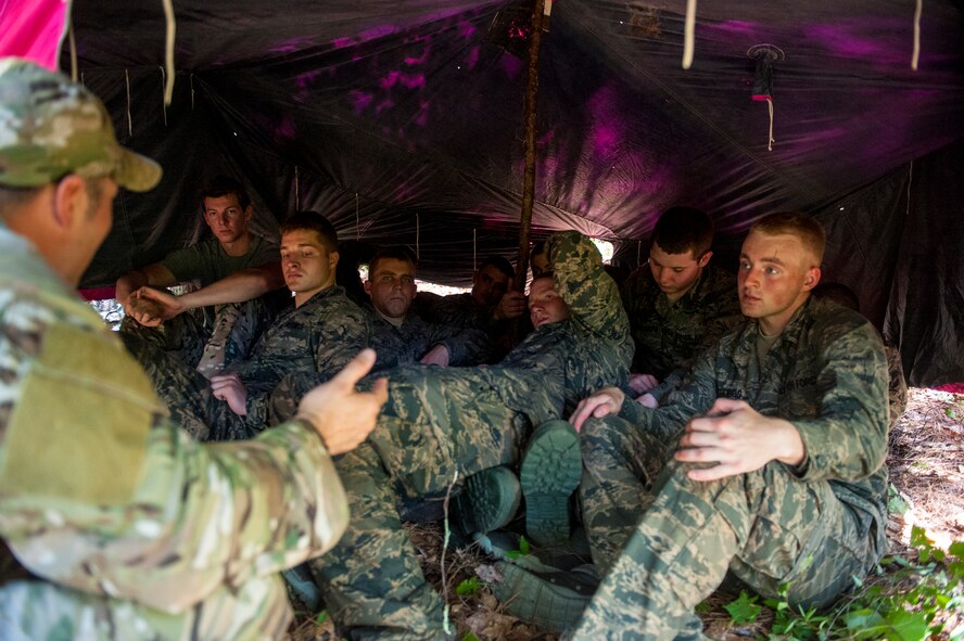 U.S. Air Force Staff Sgt. Christopher Osnes(far left), 38th Rescue Squadron Survival, Evasion, Resistance and Escape specialist, explains the importance of teamwork and using nature to survive during a SERE  class at Moody Air Force Base, Ga., June 17, 2014. Instructors tasked the cadets with working together to build a shelter within a specified time. (U.S. Air Force photo by Airman 1st Class Ceaira Tinsley/Released)