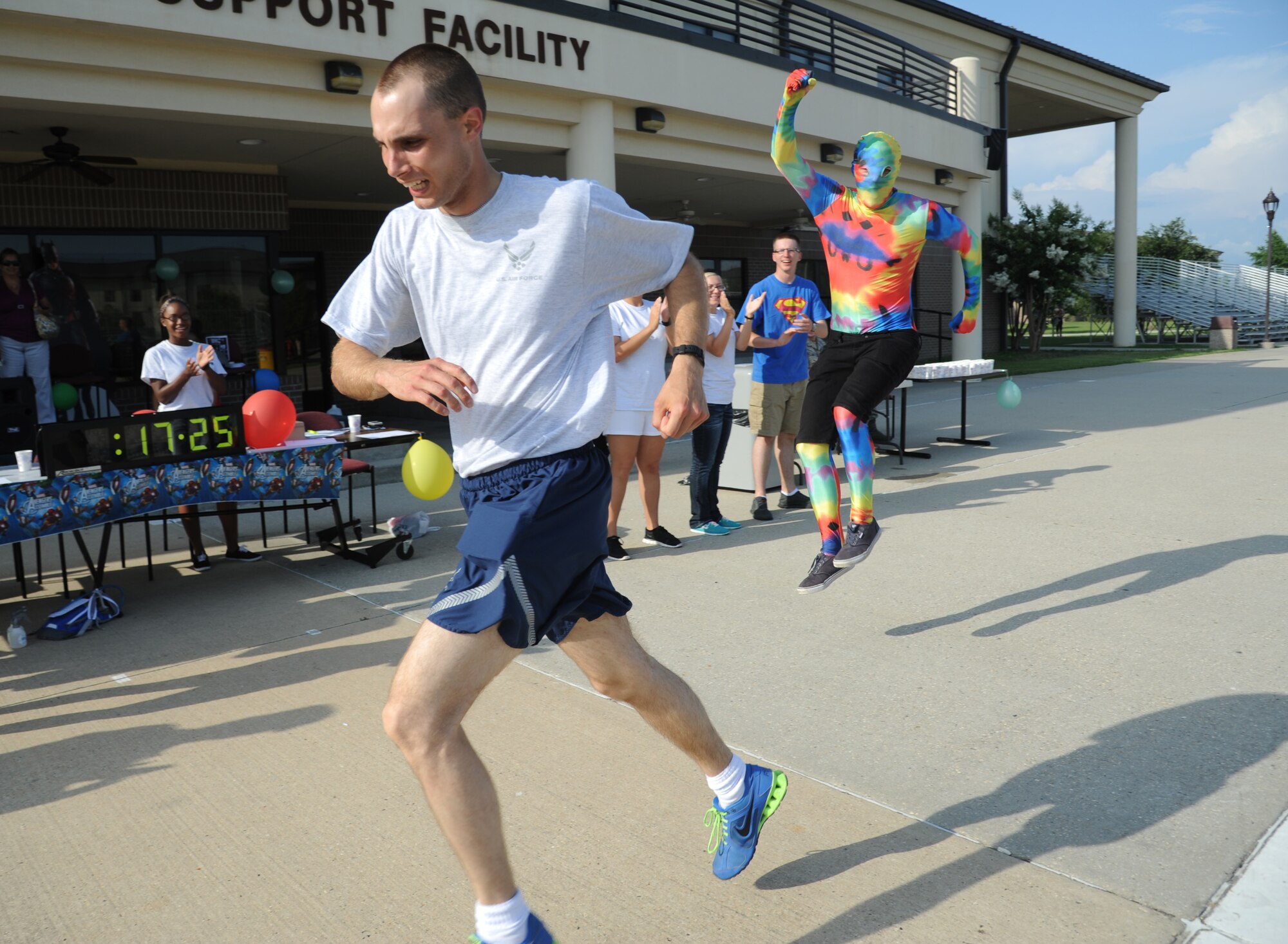 Airman 1st Class Paul Krukowski, 336th Training Squadron, finishes a 5K run with a time of 17 minutes 25 seconds as Airman Basic Peter Litman, 335th Training Squadron, cheers him on June 19, 2014, at the Triangle, Keesler Air Force Base, Miss.  The super hero themed event hosted by the 81st Training Group teal rope program raised more than $1,300 for the Gulf Coast Women’s Shelter for Non-Violence.  (U.S. Air Force photo by Kemberly Groue)