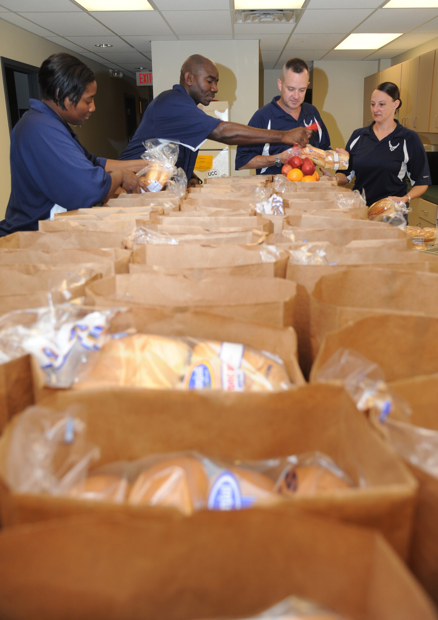 Senior Master Sgt. Lisbeth Farnum, 81st Aerospace Medicine Squadron, Master Sgt. Michael Davis, 81st Medical Operations Squadron, Master Sgt. Charles Sargent, 81st Medical Support Squadron, and Master Sgt. Laurie Holmes, 81st Training Wing, represent the Keesler Air Force Base Top III as they pack groceries into bags for families June 18, 2014, at Back Bay Mission in Biloxi, Miss.  The Top III raised more than $1,500 for the Back Bay Mission “Summer Food Program” which was used to purchase a one-week supply of food for 50 families. (U.S. Air Force photo by Kemberly Groue)